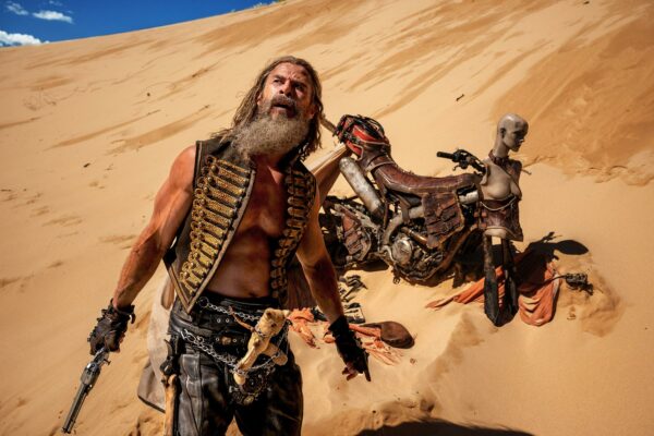 Dementus (Chris Hemsworth) at the bottom of a sand dune with a motorcycle behind him