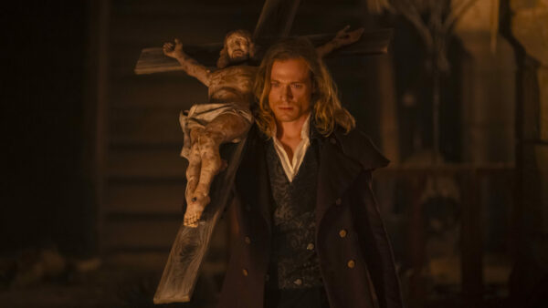 Lestat (Sam Reid) carries a large cross