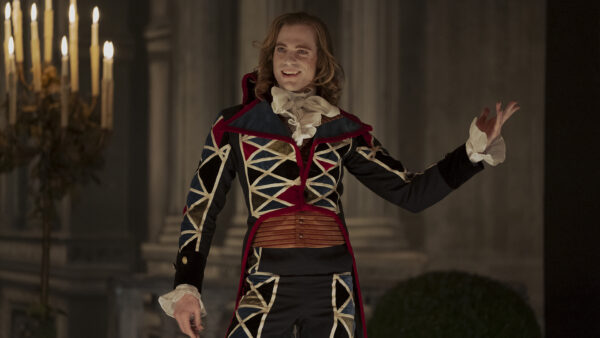 Lestat (Sam Reid) grins on stage in a red and blue stitched outfit