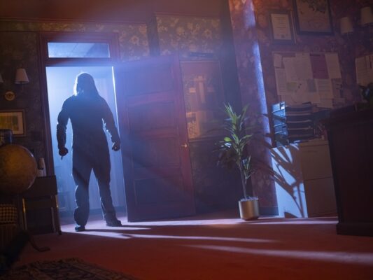 Serial killer A stands in front of a brightly lit door