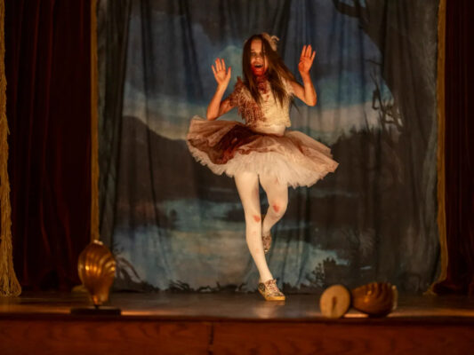 A bloodied Abigail (Alisha Weir) dances in a tutu on stage