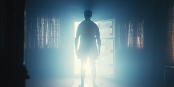 Bar Man (Pierre Yves Charbonneau) stands bathed in the white light of an open fridge door