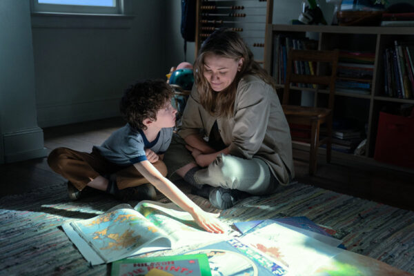 Pre-teen Arlo (Caleb Dolden) points at a map while his mom Maggie (Yvonne Strahovski) shines a flashlight on it